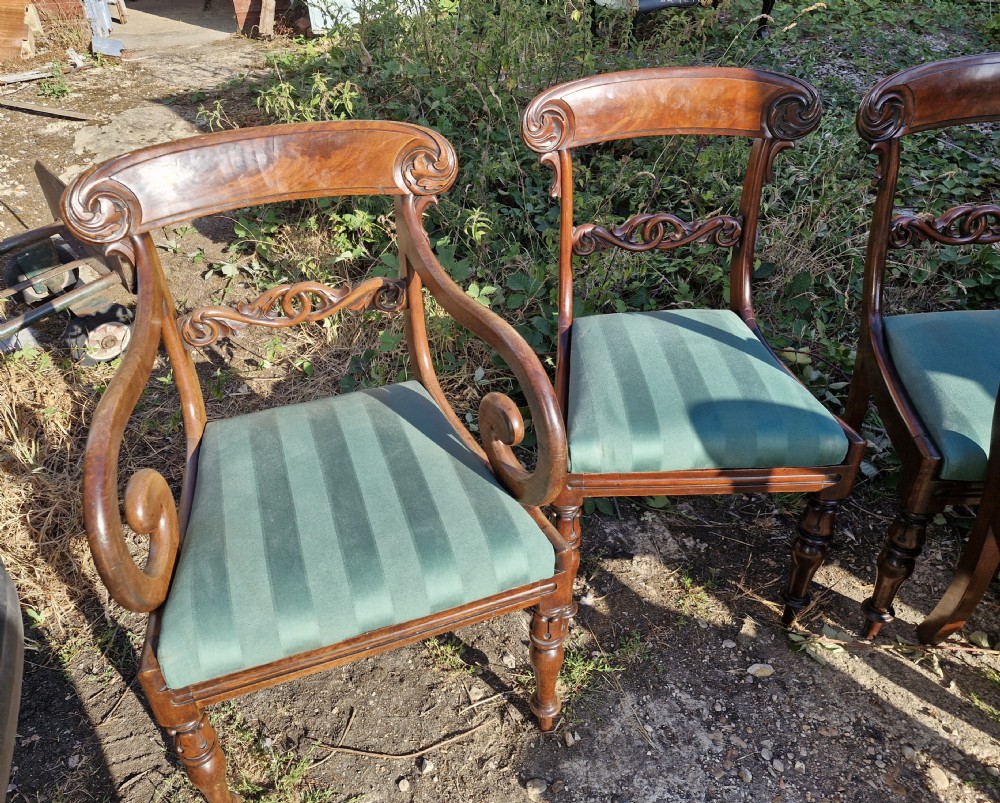 A set of eight Regency mahogany dining chairs featuring scroll-carved crest rails, decorative central splats, green striped fabric seats, and turned front legs. View III