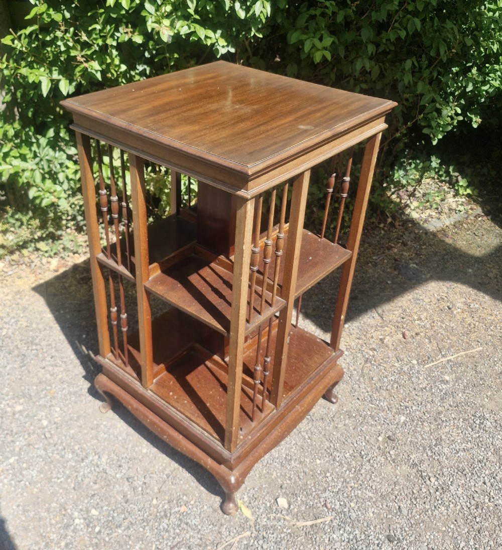 An Edwardian mahogany revolving bookcase featuring open square shelving with vertical turned spindles and a moulded top. View V