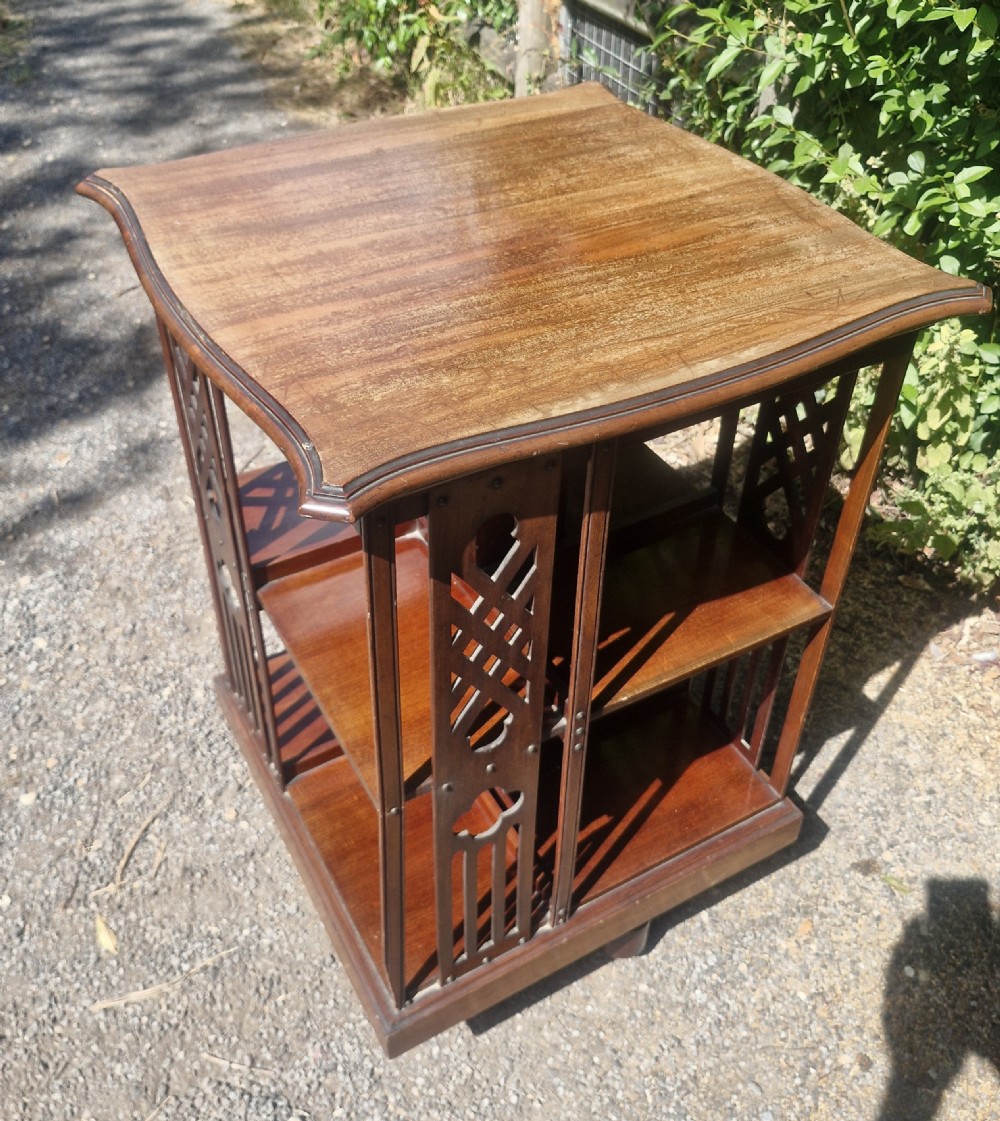 An Edwardian mahogany revolving bookcase featuring a square moulded top surface and pierced fretwork side panels. View II