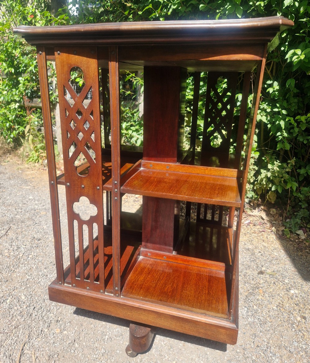 An Edwardian mahogany revolving bookcase featuring a square moulded top surface and pierced fretwork side panels. View IV