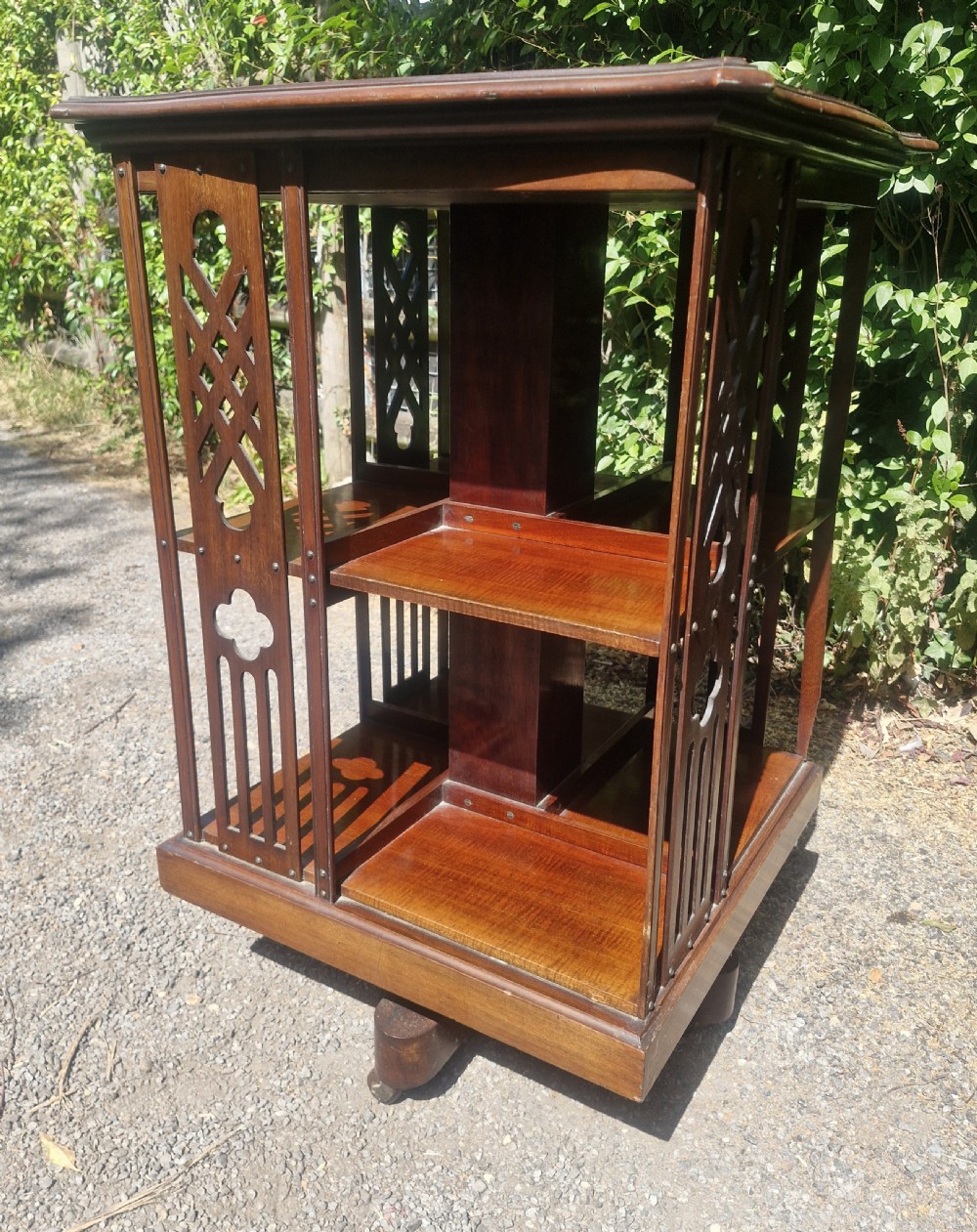 An Edwardian mahogany revolving bookcase featuring a square moulded top surface and pierced fretwork side panels. View V