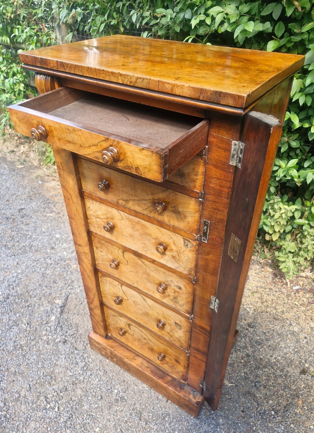 A tall Victorian walnut Wellington chest featuring seven stacked drawers with turned wooden knobs, carved upper corbels, and a side locking pilaster bar. View II