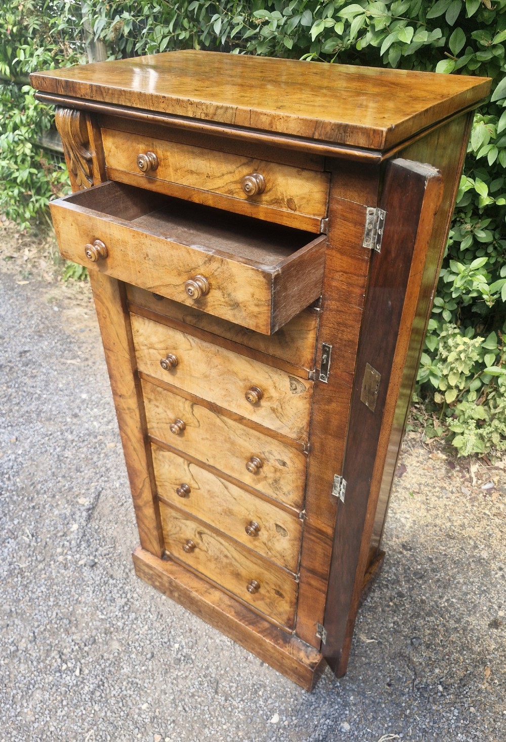 A tall Victorian walnut Wellington chest featuring seven stacked drawers with turned wooden knobs, carved upper corbels, and a side locking pilaster bar. View III