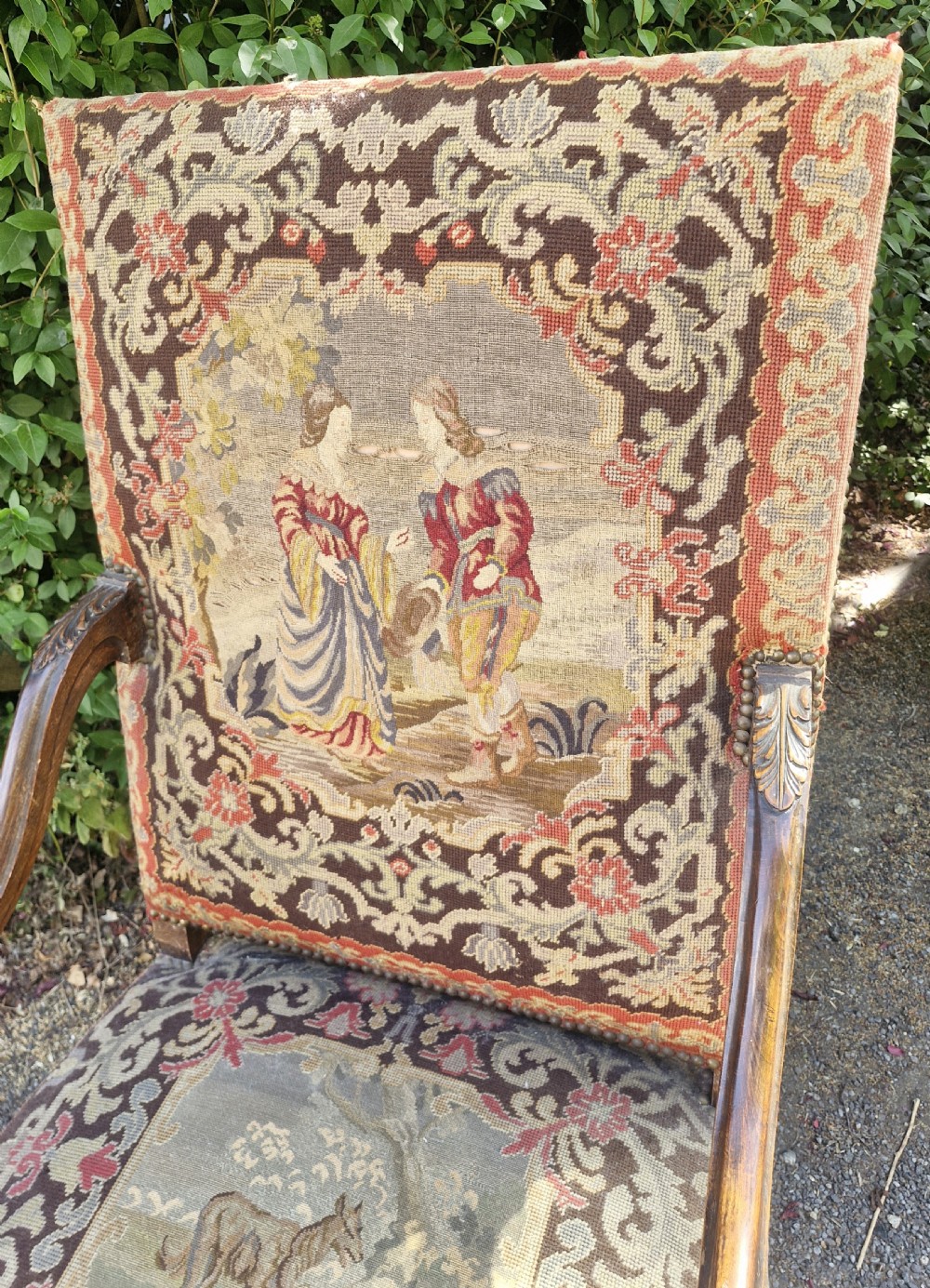 A late nineteenth-century high-back armchair featuring an intricately carved timber frame, scroll arms, cabriole legs, and pictorial needlework upholstery trimmed with brass studs. View VIII