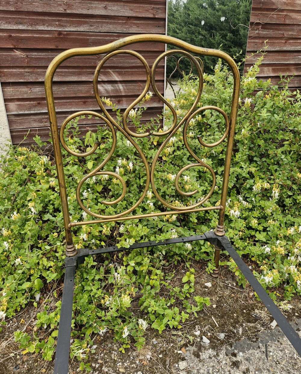 A matching pair of brass single bedsteads featuring decorative curved scrollwork headboards and footboards with black iron side rails. View III