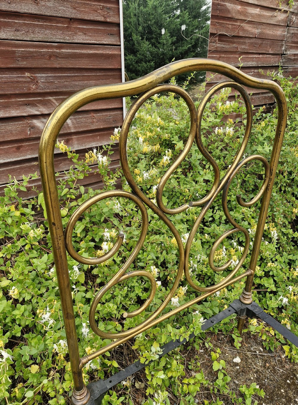 A matching pair of brass single bedsteads featuring decorative curved scrollwork headboards and footboards with black iron side rails. View IX