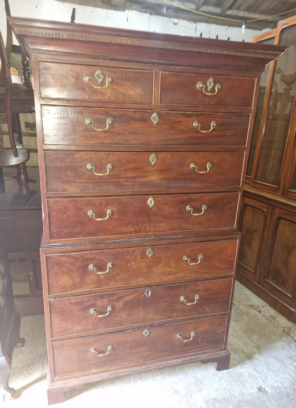 A late Georgian tall mahogany chest on chest featuring two short drawers over six long drawers with brass handles and a dentil cornice. View VIII