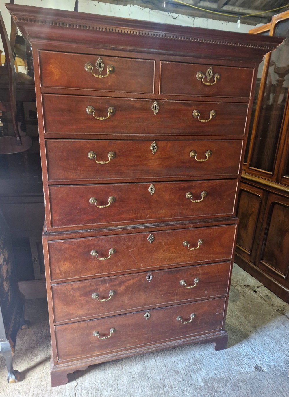 A late Georgian tall mahogany chest on chest featuring two short drawers over six long drawers with brass handles and a dentil cornice. View IX