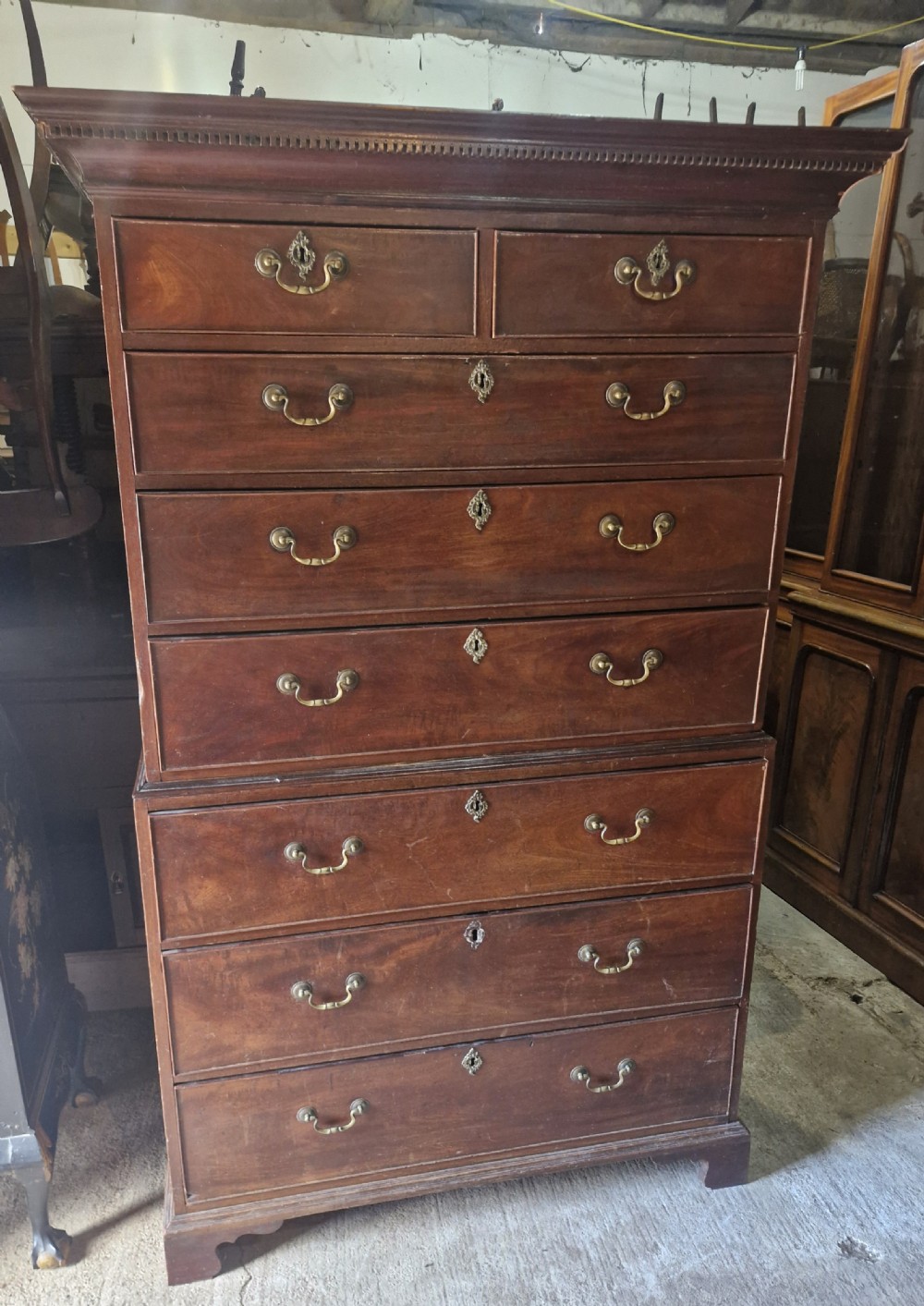 A late Georgian tall mahogany chest on chest featuring two short drawers over six long drawers with brass handles and a dentil cornice. View X