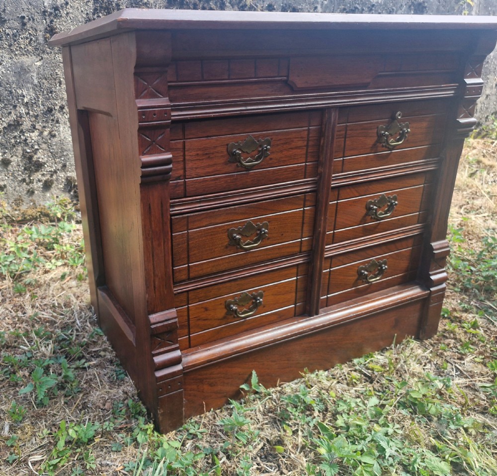 A warm brown mahogany desktop bank of six drawers featuring carved pilasters, grooved drawer fronts, and brass drop handles. View IV