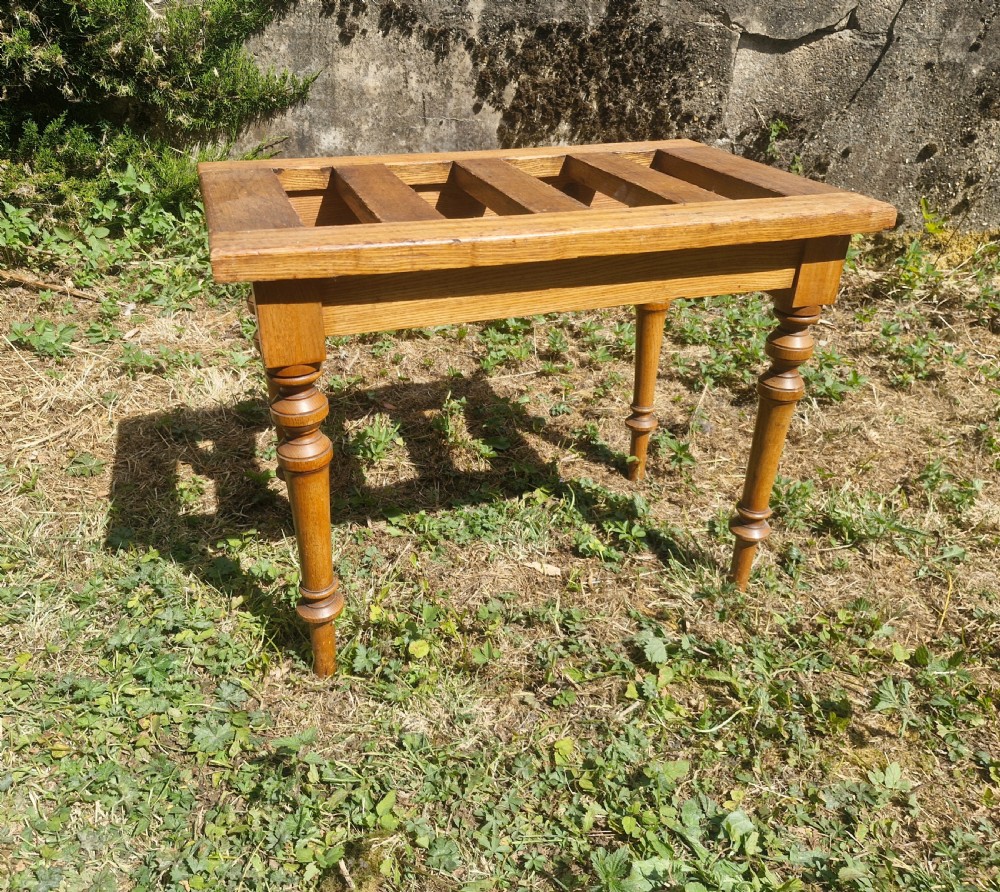 An Edwardian ash luggage stand with a rectangular slatted timber top and four turned wooden legs.