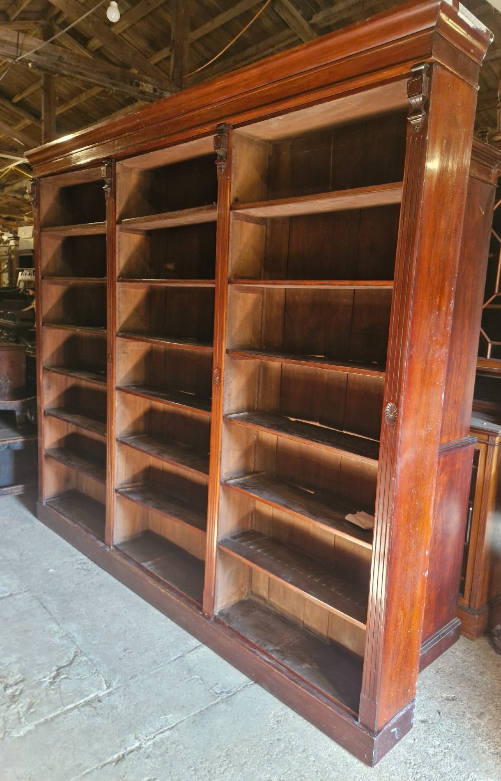 A large, three-section antique mahogany open-front bookcase with adjustable shelves and fluted pilasters. View II