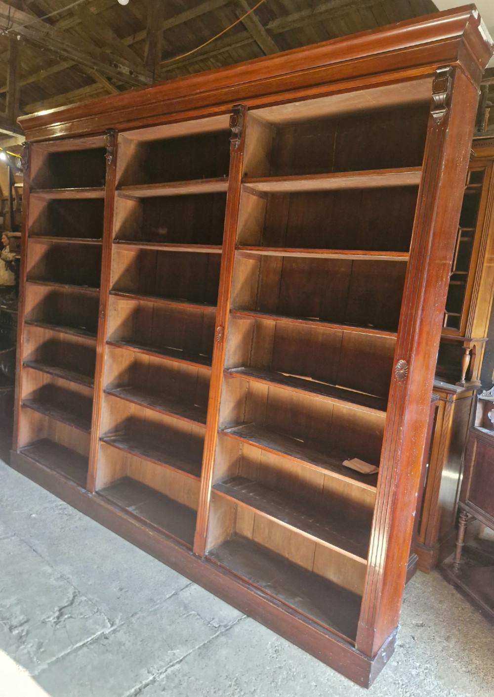 A large, three-section antique mahogany open-front bookcase with adjustable shelves and fluted pilasters. View VI