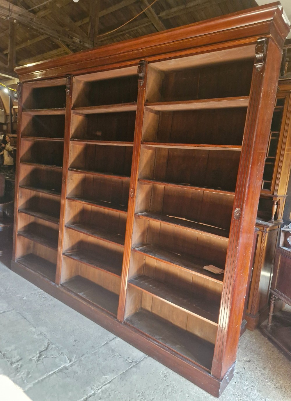 A large, three-section antique mahogany open-front bookcase with adjustable shelves and fluted pilasters. View IX