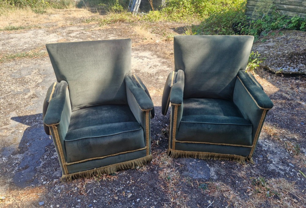 A pair of olive green velvet Knole armchairs featuring drop-side arms with finial ties, gold piping, and lower fringe trim. View V