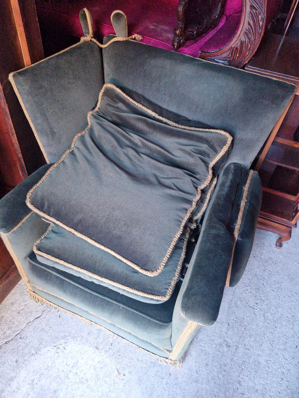 A pair of olive green velvet Knole armchairs featuring drop-side arms with finial ties, gold piping, and lower fringe trim. View VII