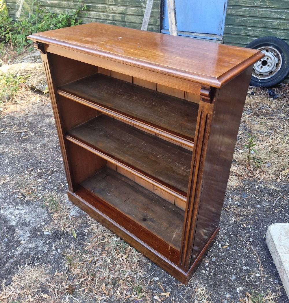 A late Victorian warm brown wooden open-front bookcase with three shelves, fluted side pilasters, and a moulded top. View V