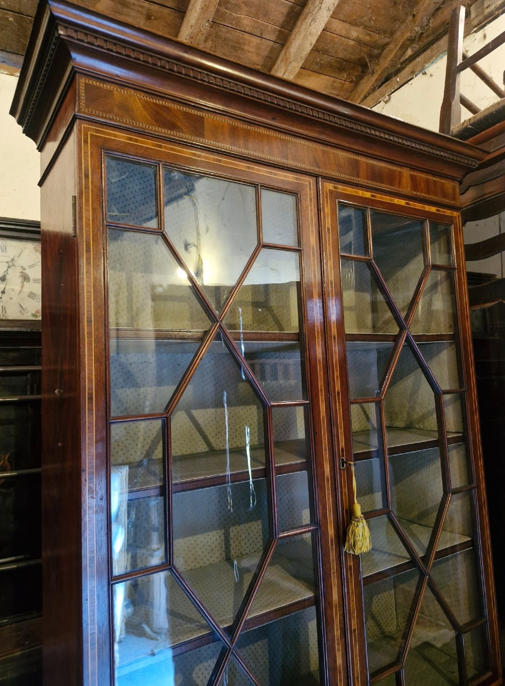 A 19th-century two-tier mahogany bookcase cabinet featuring astragal glazed upper doors, a single long drawer, and inlaid double lower doors on bracket feet. View V