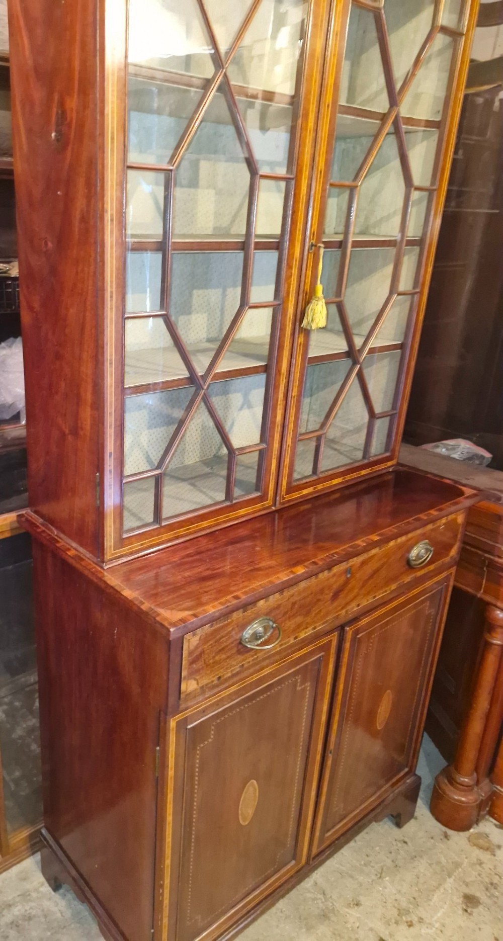 A 19th-century two-tier mahogany bookcase cabinet featuring astragal glazed upper doors, a single long drawer, and inlaid double lower doors on bracket feet. View VII