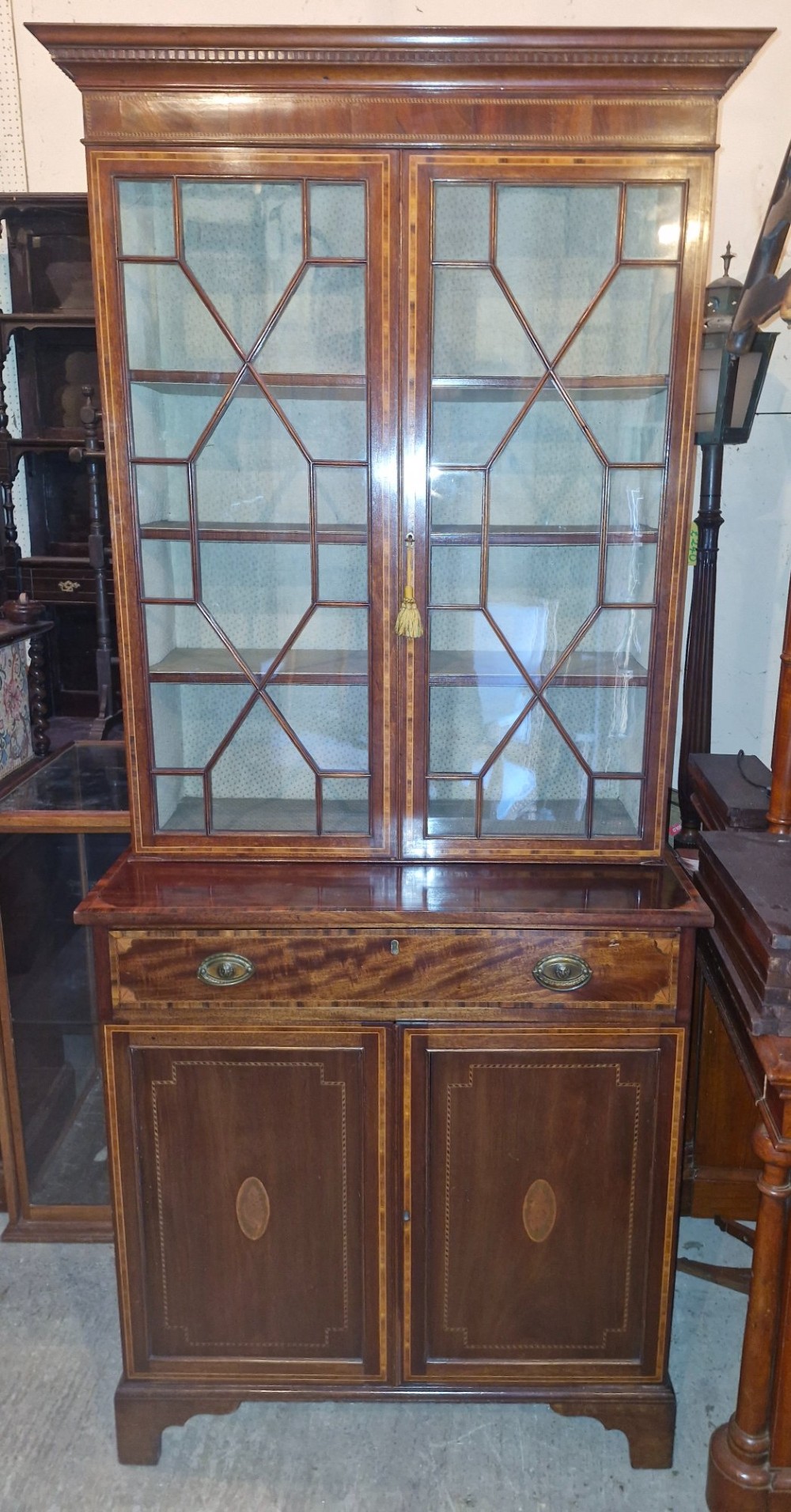A 19th-century two-tier mahogany bookcase cabinet featuring astragal glazed upper doors, a single long drawer, and inlaid double lower doors on bracket feet. View X