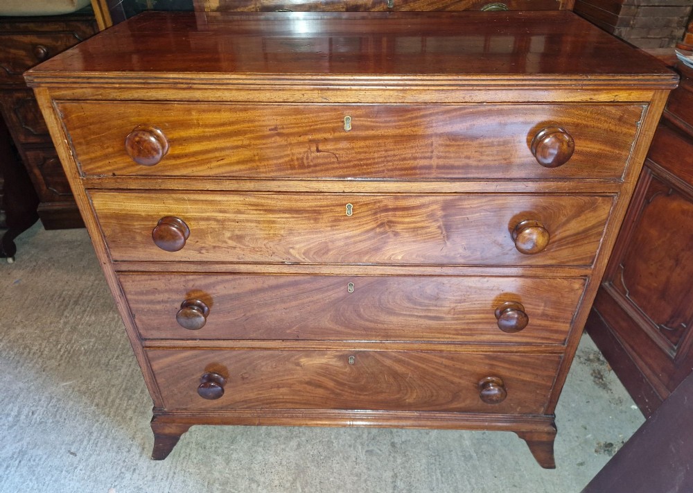 An early nineteenth-century mahogany chest of drawers featuring four graduated drawers with turned wooden knobs and bracket feet. View II