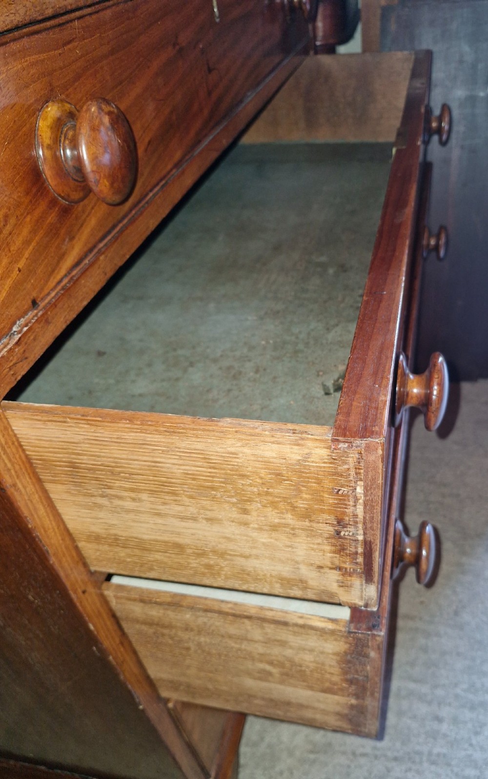 An early nineteenth-century mahogany chest of drawers featuring four graduated drawers with turned wooden knobs and bracket feet. View III