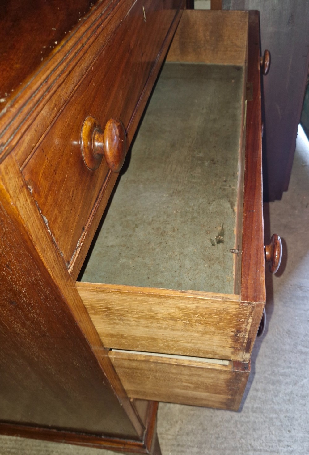 An early nineteenth-century mahogany chest of drawers featuring four graduated drawers with turned wooden knobs and bracket feet. View IV
