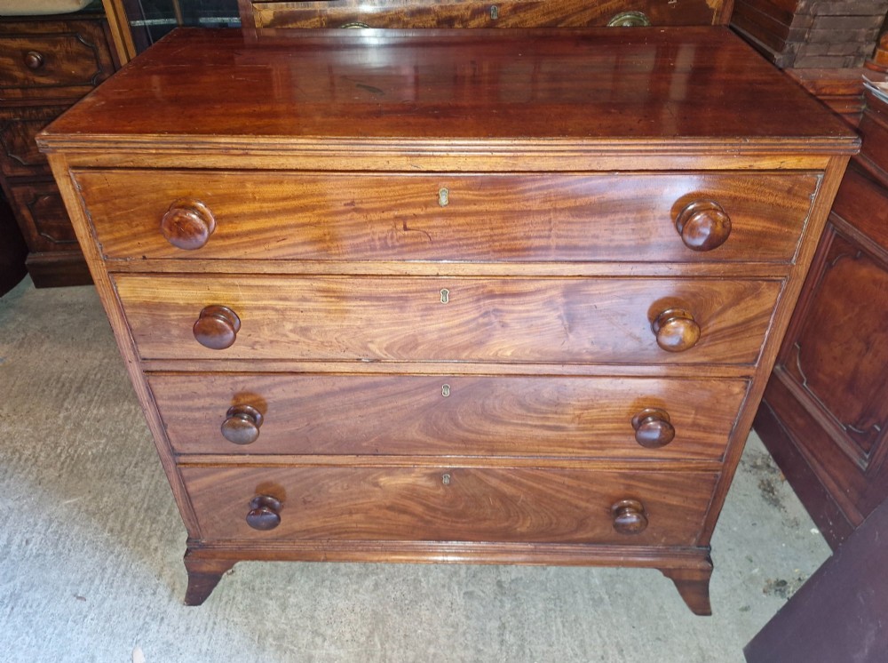 An early nineteenth-century mahogany chest of drawers featuring four graduated drawers with turned wooden knobs and bracket feet. View V