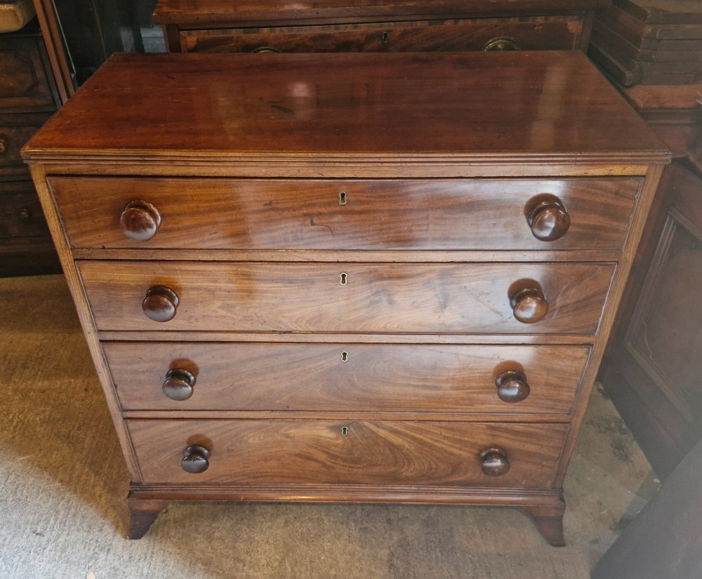 An early nineteenth-century mahogany chest of drawers featuring four graduated drawers with turned wooden knobs and bracket feet. View VI