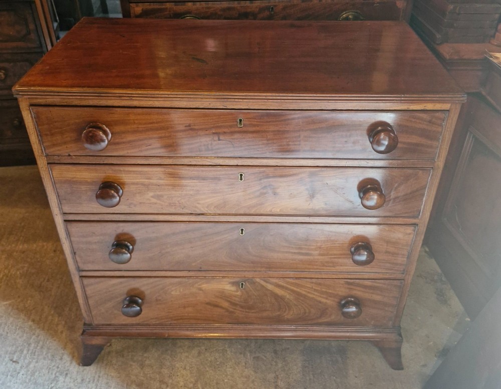 An early nineteenth-century mahogany chest of drawers featuring four graduated drawers with turned wooden knobs and bracket feet. View VII