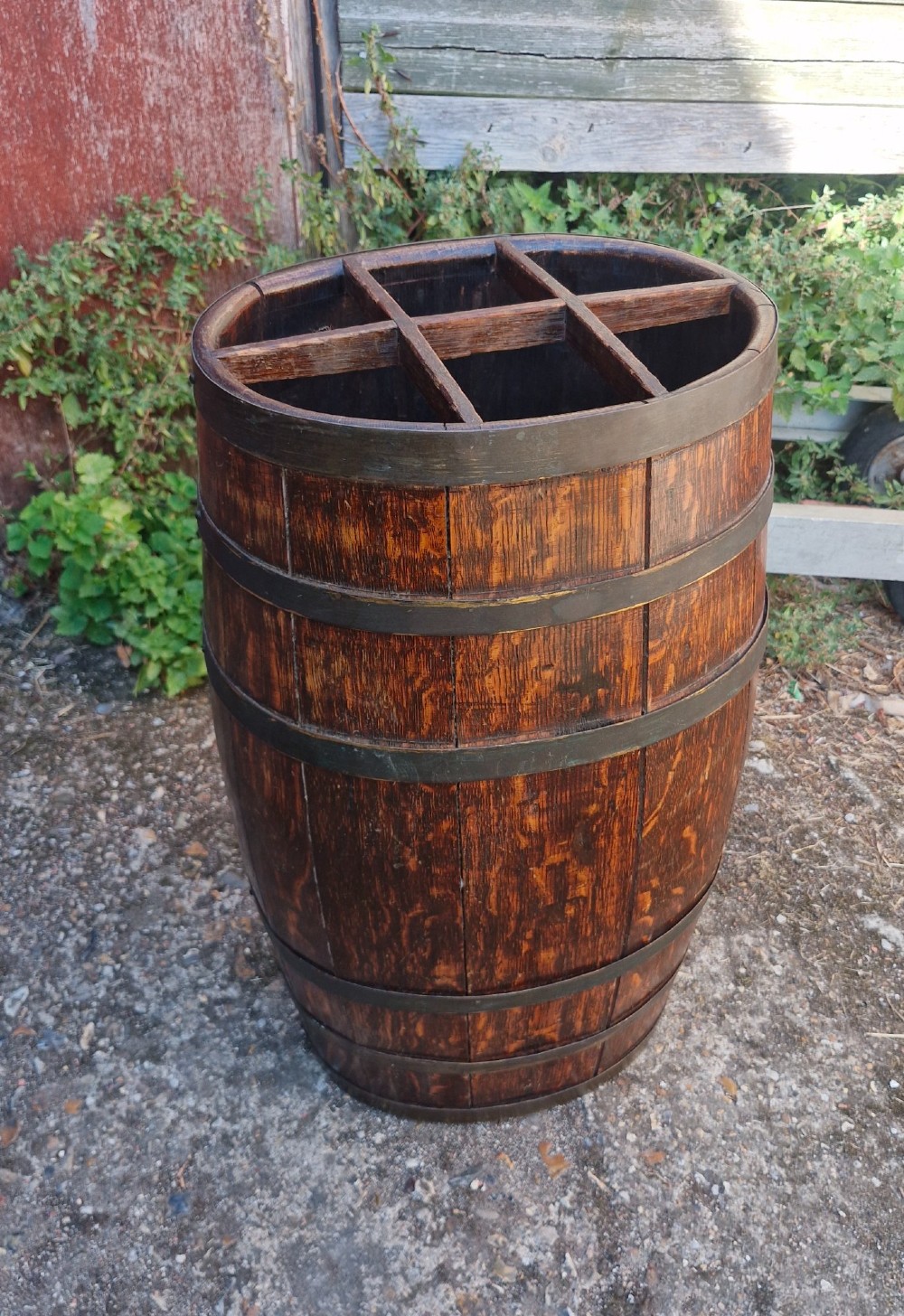 A dark oak coopered barrel stick stand featuring metal binding hoops and a six-section wood divider at the top.
