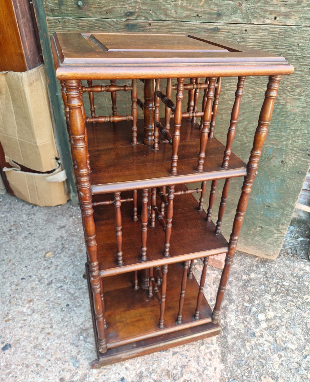A dark mahogany three-tier revolving bookcase with vertical turned spindles and a square raised top panel. View II