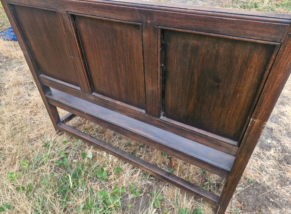 A dark oak hall bench featuring a triple-panelled backrest, scrolled armrests, turned front legs, and a solid wooden seat. View II
