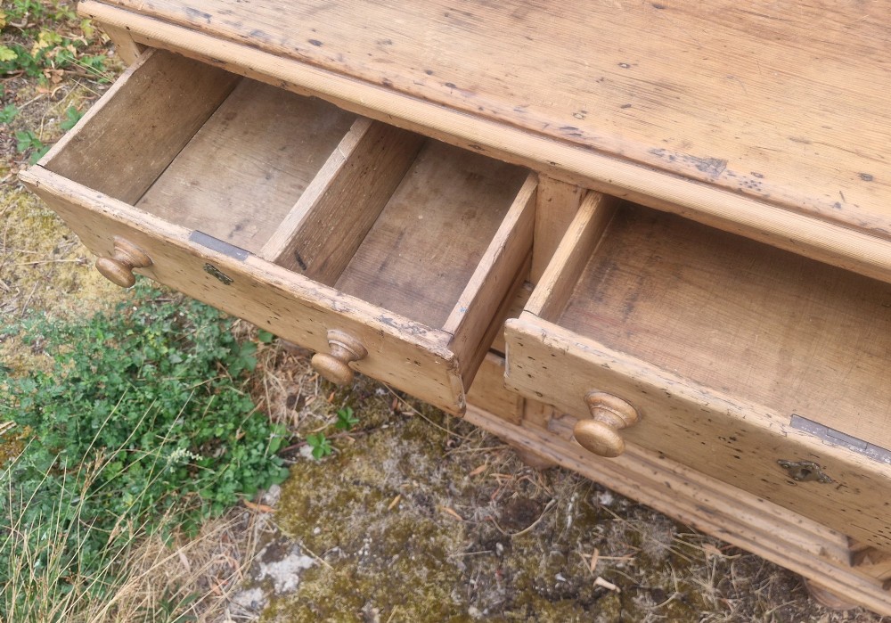 A wide Victorian pine dresser base featuring multiple drawers with turned wooden handles flanking a central double cupboard, resting on turned feet. View VII