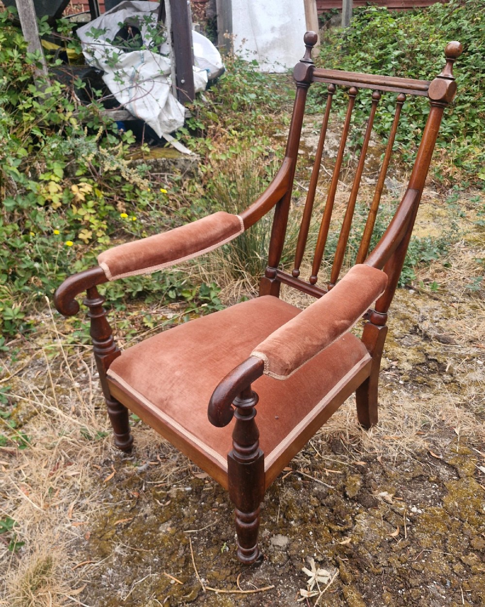 An early Victorian mahogany armchair featuring a spindle backrest, padded velvet armrests, a cushioned brown velvet seat, and turned wooden front legs. View V