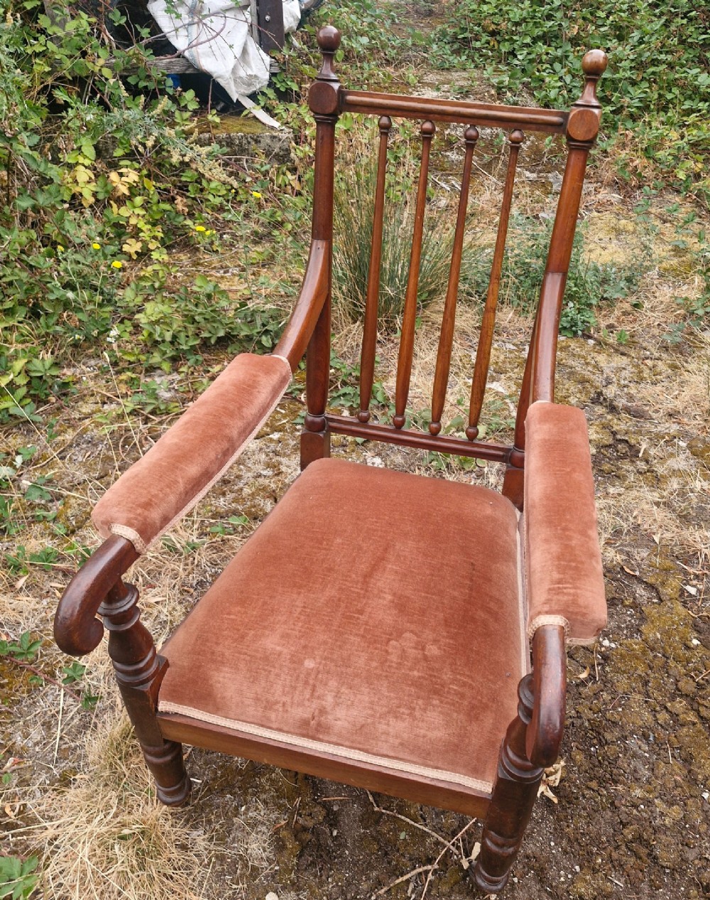 An early Victorian mahogany armchair featuring a spindle backrest, padded velvet armrests, a cushioned brown velvet seat, and turned wooden front legs. View VI