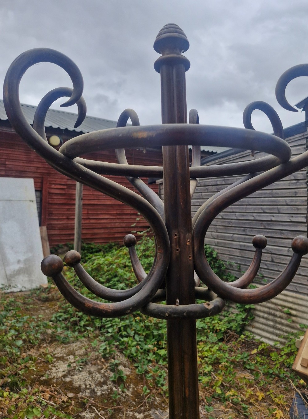 An early twentieth-century dark brown bentwood freestanding hat and coat stand featuring scrolled upper hooks, a mid-height umbrella ring, and splayed legs. View V