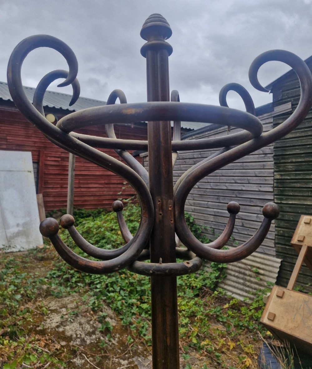 An early twentieth-century dark brown bentwood freestanding hat and coat stand featuring scrolled upper hooks, a mid-height umbrella ring, and splayed legs. View VI