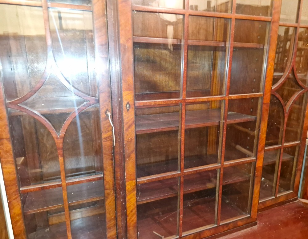 An early twentieth century dark mahogany breakfront bookcase cabinet featuring glazed doors with geometric astragal glazing bars above a cupboard base. View VI