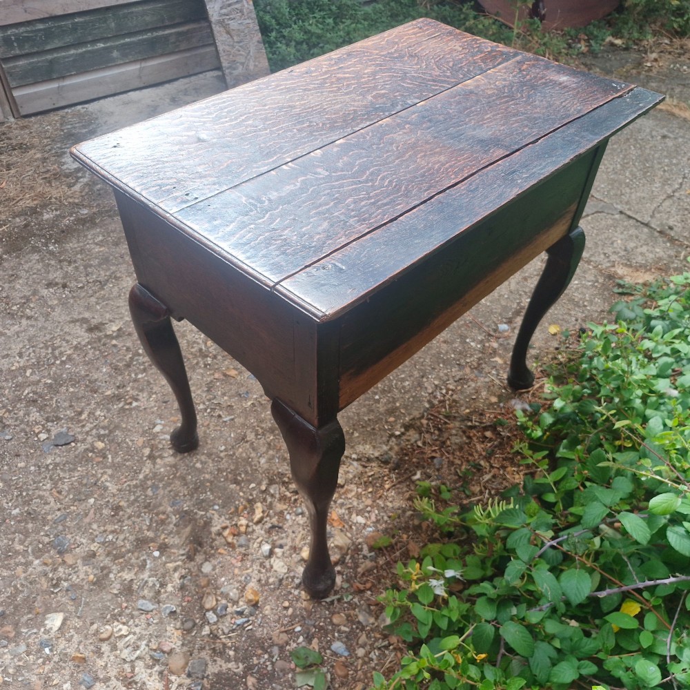 A mid-18th century dark oak side table with three drawers, brass handles, and cabriole legs on pad feet. View II