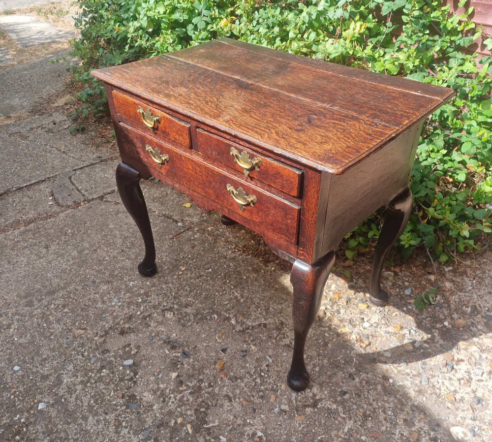 A mid-18th century dark oak side table with three drawers, brass handles, and cabriole legs on pad feet. View VI