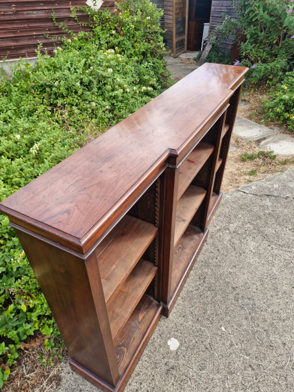 A low, three-bay open mahogany breakfront bookcase featuring adjustable wooden shelves and a solid plinth base. View II