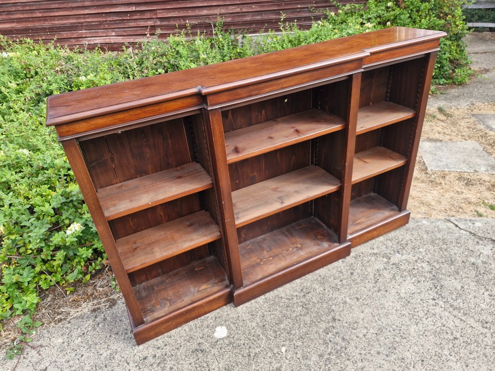A low, three-bay open mahogany breakfront bookcase featuring adjustable wooden shelves and a solid plinth base. View V