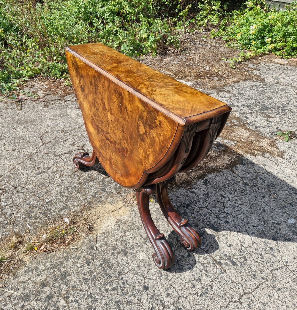 A Victorian burr walnut scissor action table featuring a shaped oval top with distinct figure grain and carved cabriole legs with a central turned stretcher finial. View II