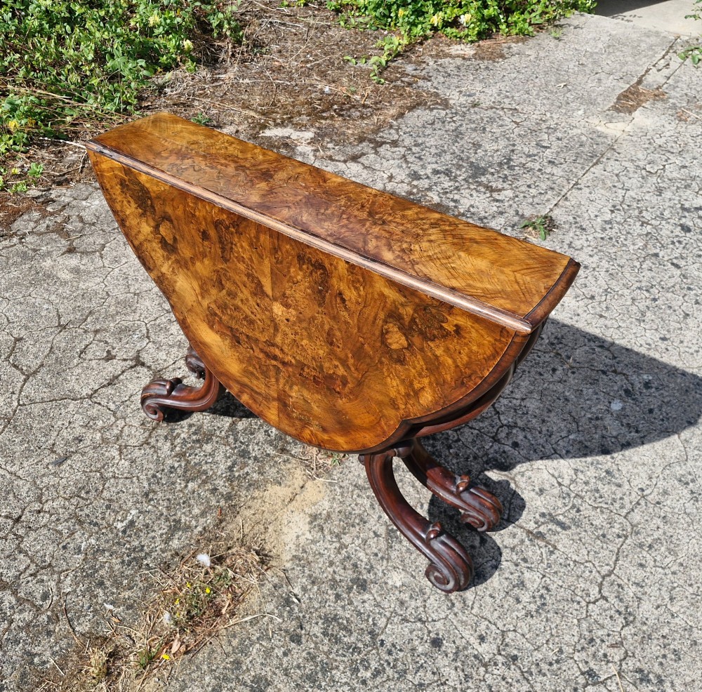 A Victorian burr walnut scissor action table featuring a shaped oval top with distinct figure grain and carved cabriole legs with a central turned stretcher finial. View III