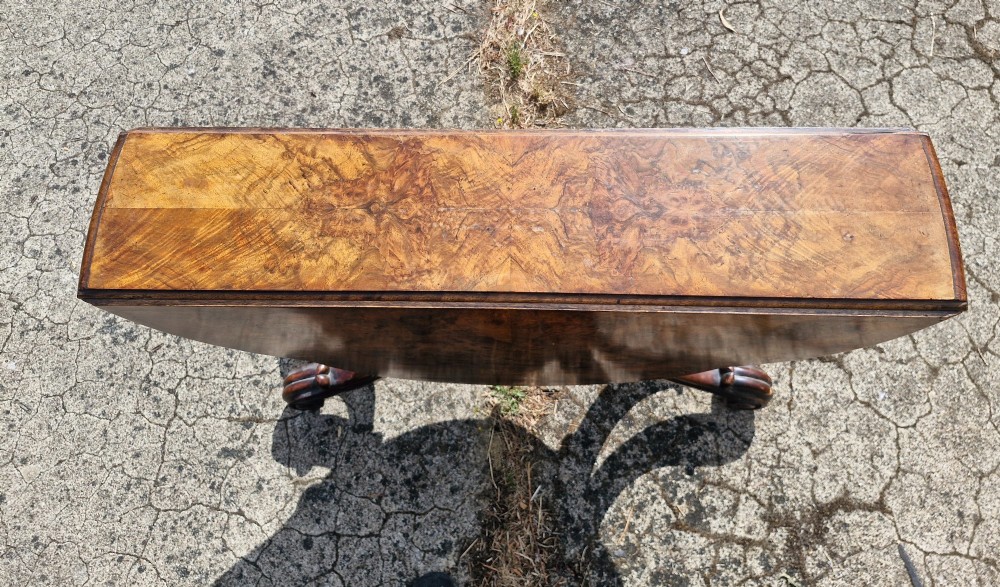 A Victorian burr walnut scissor action table featuring a shaped oval top with distinct figure grain and carved cabriole legs with a central turned stretcher finial. View IV