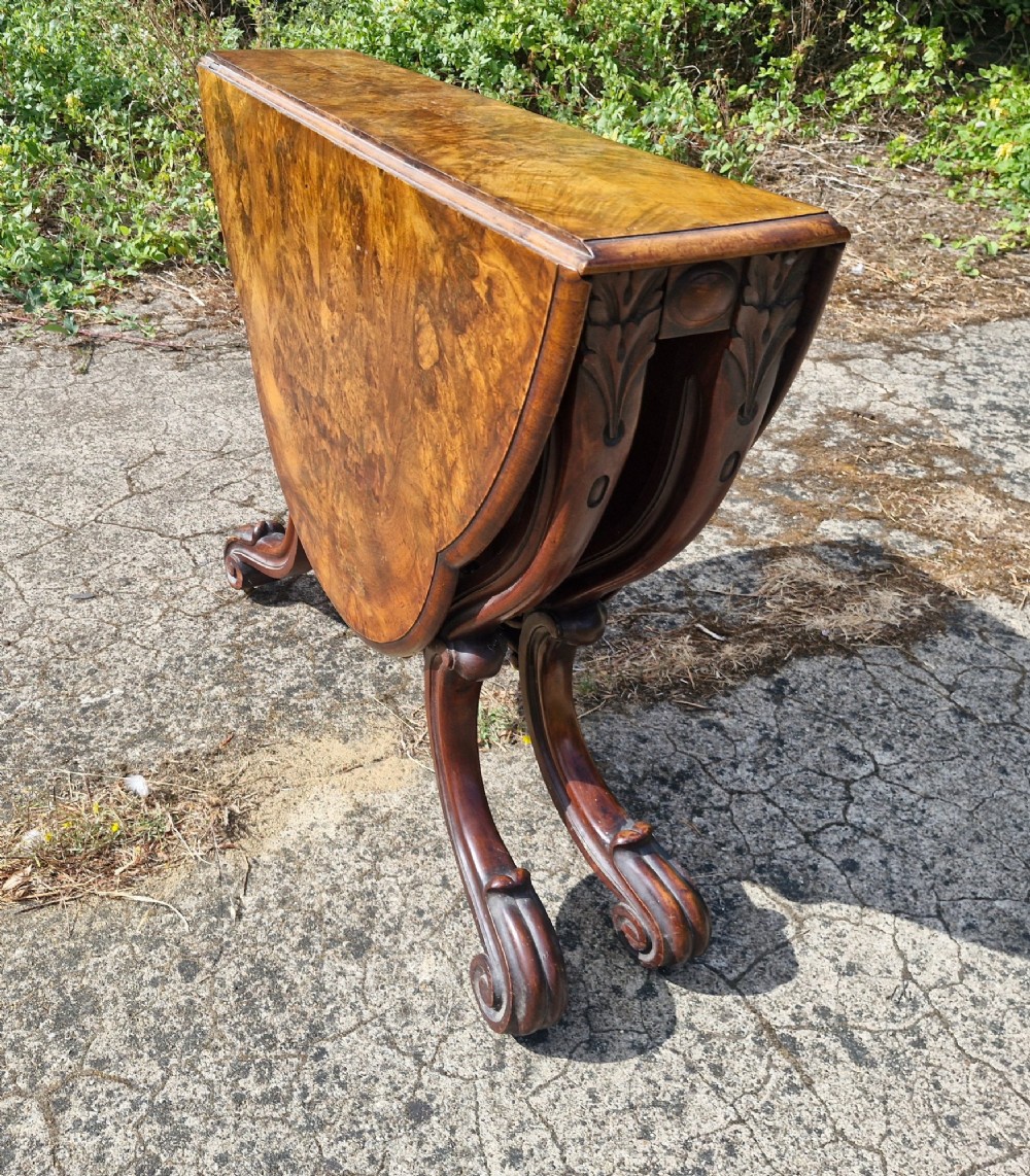 A Victorian burr walnut scissor action table featuring a shaped oval top with distinct figure grain and carved cabriole legs with a central turned stretcher finial. View VII