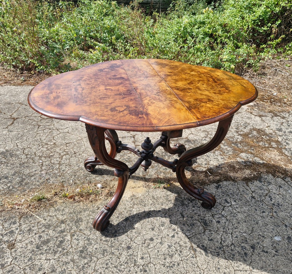A Victorian burr walnut scissor action table featuring a shaped oval top with distinct figure grain and carved cabriole legs with a central turned stretcher finial. View VIII