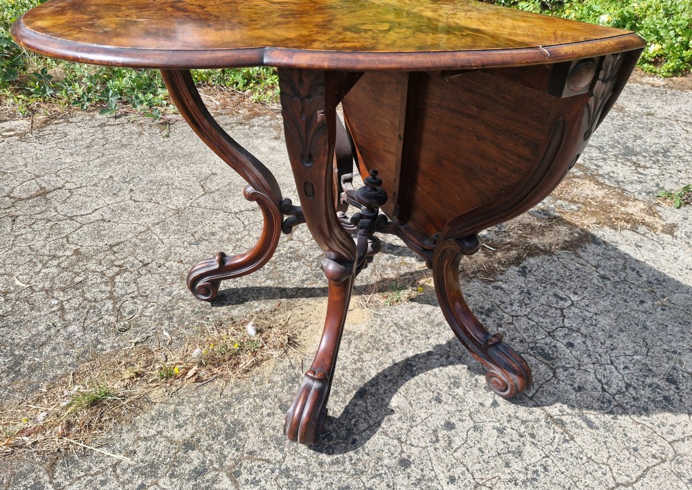 A Victorian burr walnut scissor action table featuring a shaped oval top with distinct figure grain and carved cabriole legs with a central turned stretcher finial. View IX