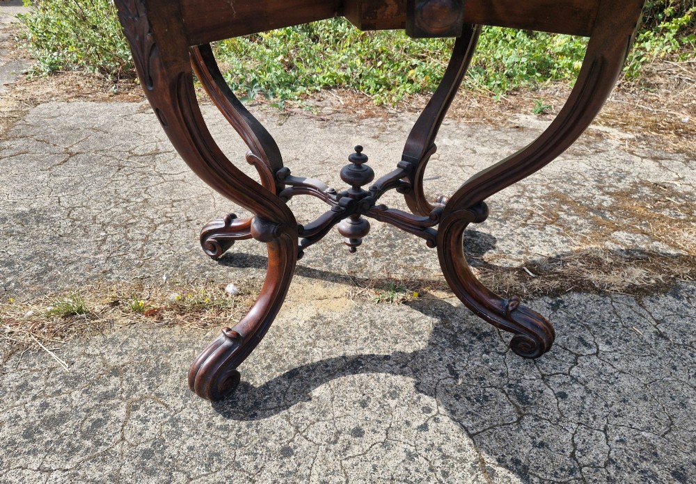 A Victorian burr walnut scissor action table featuring a shaped oval top with distinct figure grain and carved cabriole legs with a central turned stretcher finial. View XI